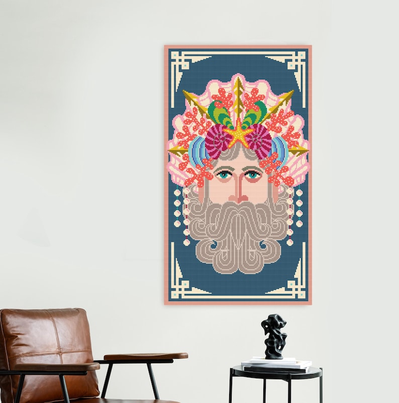 K&ouml;nnte beinhalten: Ein gerahmtes Kreuzstich-Kunstwerk mit einem stilisierten Gesicht mit langem, grauem Bart und einer farbenfrohen Krone aus Korallen und Muscheln. Das Kunstwerk ist vor einem blauen Hintergrund mit einem rosa Rahmen angeordnet.