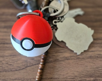 May include: A red and white Pokeball keychain with a black band around the middle. The keychain is attached to a silver key ring and a brown beaded chain.