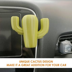 May include: A green cactus-shaped car air freshener. The air freshener is attached to the dashboard of a car. The text "UNIQUE CACTUS DESIGN MAKE IT A GREAT ADDITION FOR YOUR CAR" is at the bottom of the image.