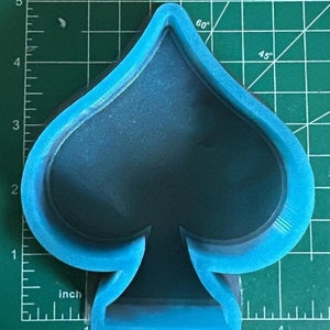 K&ouml;nnte beinhalten: Eine blaue Silikonform in Form einer Pik-Spielkarte. Die Form ist etwa 10 cm hoch und 7,5 cm breit.