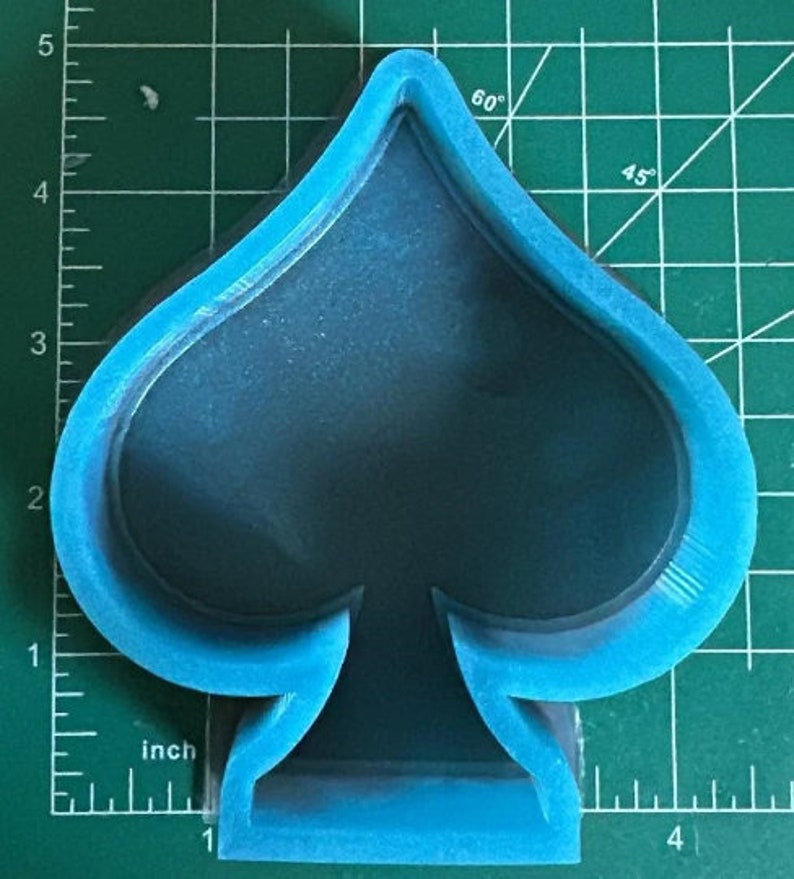 K&ouml;nnte beinhalten: Eine blaue Silikonform in Form einer Pik-Spielkarte. Die Form ist etwa 10 cm hoch und 7,5 cm breit.