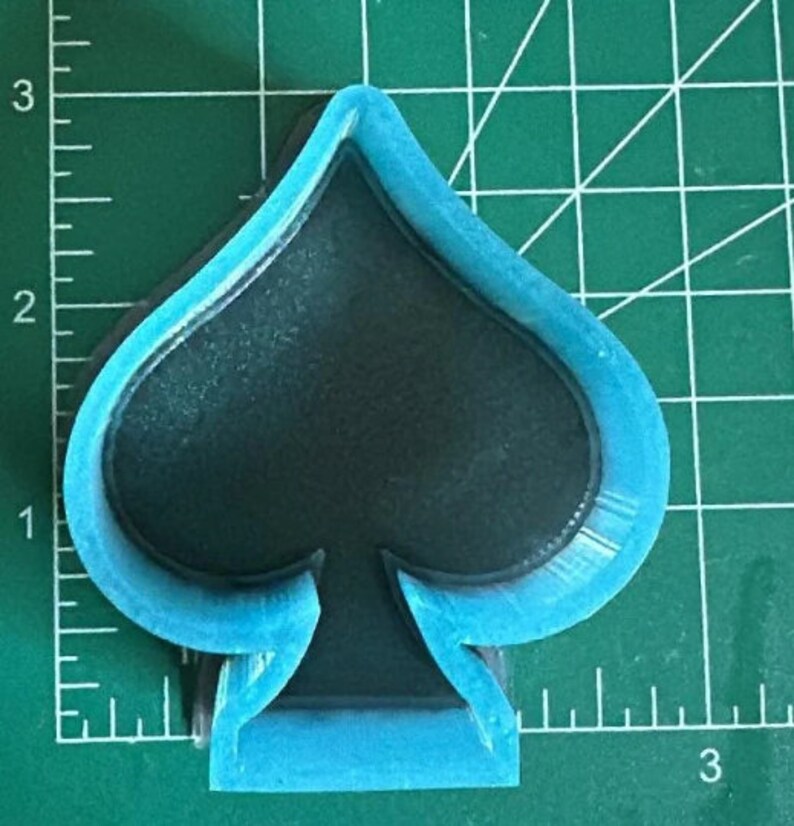 K&ouml;nnte beinhalten: Ein blauer Plastik-Ausstecher in Form eines Pik-Spielkartensymbols.