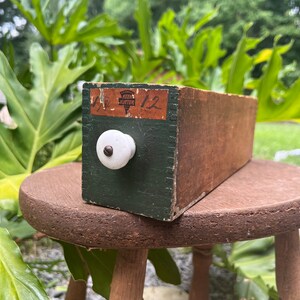 May include: A wooden box with a green painted front and a white knob. The box has a label that reads "Keen Kutter 1/2 12".