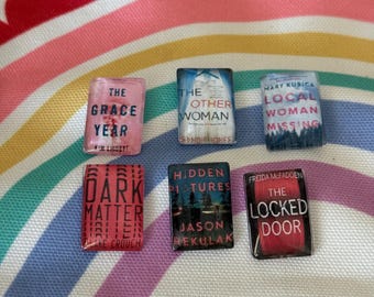 Könnte beinhalten: Sechs verschiedene Buchcover mit Titeln und Autorennamen. Die Cover sind alle in verschiedenen Farben gehalten und haben unterschiedliche Designs. Die Bücher handeln alle von Mystery und Spannung.