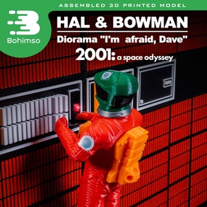 May include: A 3D printed model of a diorama featuring a figure in a red space suit and a green helmet, standing in front of a red and black panel with white buttons. The diorama is titled "HAL & BOWMAN" and "2001: a space odyssey". The diorama is 9 inches wide.
