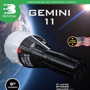 Puede incluir: Un modelo 3D impreso ensamblado de la nave espacial Gemini 11, listo para exhibir. El modelo mide 23 cm de largo e incluye una placa base especial y una pegatina para portátil de 7,6 cm. La nave espacial es de color negro y blanco con detalles rojos y tiene la inscripción "Estados Unidos" en el lateral.