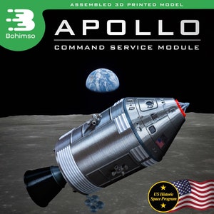 May include: A 3D printed model of the Apollo Command Service Module, assembled and displayed on a lunar surface. The model is 8.5 inches long and includes a special baseplate. The model is painted silver and features a red and white American flag.