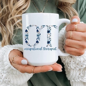 May include: White ceramic mug with a floral design spelling out "OT" for occupational therapist.