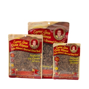 May include: Three resealable bags of Carne Seca Doña Blanca Gourmet Dried Beef. The bags are red, white, and gold with a picture of a woman on each. The bags are labeled with the product name, weight, and nutritional information. The bags are filled with dried beef.