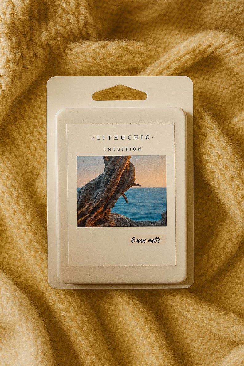May include: A white wax melt package with the text "LITHOCHIC" and "INTUITION". The package features an image of driftwood against a seascape. The package contains 6 wax melts and is set against a yellow knitted background.