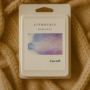 May include: A package of six wax melts, labeled "LITHOCHIC MANIFEST." The label features a watercolor design in shades of purple and blue, with the word "Manifest" in a stylized font. The package is white and sits on a beige knitted surface.