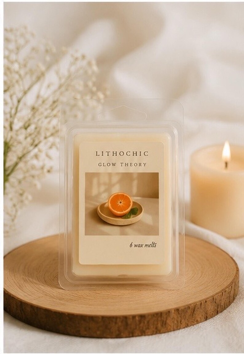 May include: A clear plastic package containing six wax melts, with the text "LITHOCHIC GLOW THEORY". The label features an image of an orange slice on a small plate. A lit candle and a wooden coaster are also in the image.