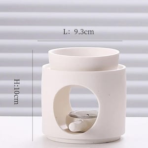 May include: A white ceramic essential oil diffuser. The diffuser is cylindrical with a circular opening and a top bowl. It measures 3.7 inches in length and 3.9 inches in height. The text on the image reads: L: 9.3cm, H: 10cm.