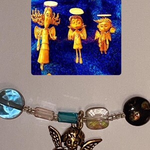 May include: A silver charm bracelet with a variety of colorful beads, including blue, green, and iridescent white. A small gold angel charm hangs from the bracelet.