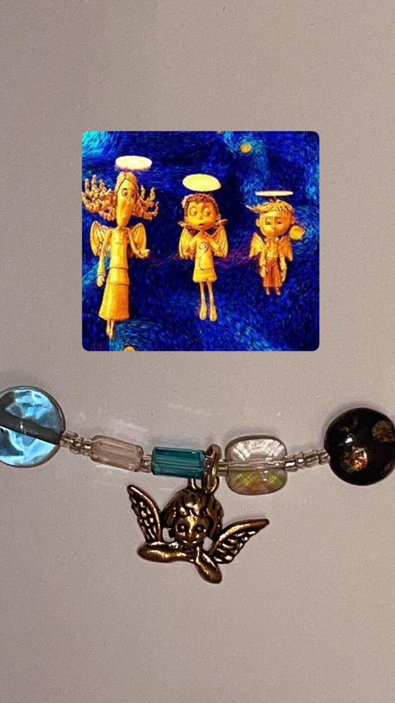 May include: A silver charm bracelet with a variety of colorful beads, including blue, green, and iridescent white. A small gold angel charm hangs from the bracelet.