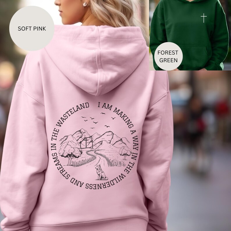 May include: A soft pink hoodie with a black graphic on the back that says "I am making a way in the wilderness and streams in the wasteland". The graphic features a mountain range, a path, and a wolf.