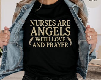 May include: Black t-shirt featuring the gold text "NURSES ARE ANGELS WITH LOVE AND PRAYER". The shirt is worn with a denim jacket. The text is centered on the front of the shirt, with feather graphics on either side.