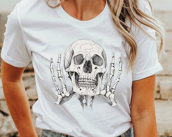 May include: White t-shirt with a black and white illustration of a skull with hands behind it.