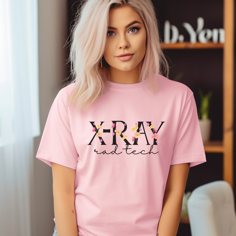 May include: Pink t-shirt with a black floral design that says "X-ray rad tech".