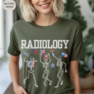 Może przedstawiać: Zielona koszulka z napisem "RADIOLOGY" w białych literach. Trzy szkielety noszą czerwono-biało-niebieskie patriotyczne czapki i akcesoria. Szkielety tańczą i trzymają amerykańskie flagi, hot dogi i balony.