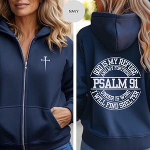 May include: A navy blue zip-up hoodie with a white cross on the front and a white circle on the back that says "God is my refuge and my fortress Psalm 91 Under His wing I will find shelter".