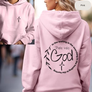 May include: Pink hoodie with a cross and the text "There was God in the waiting in the searching in the healing in the hurting" on the back.