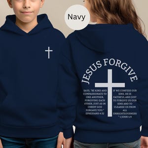 May include: Navy blue hoodie with a white cross on the front and the words "Jesus Forgive" and related text on the back. The hoodie has a front pocket and a hood.