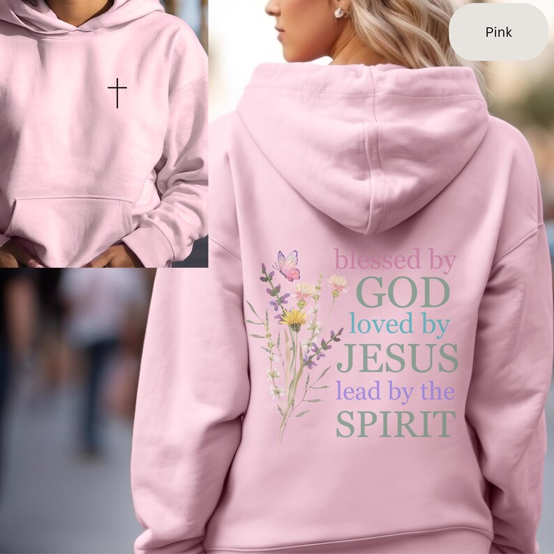 Pu&ograve; includere: Felpa con cappuccio rosa con una croce sul davanti e il testo "blessed by GOD loved by JESUS lead by the SPIRIT" sul retro. Il design sul retro include anche una farfalla ed elementi floreali.