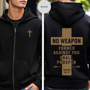 May include: Black zip-up hoodie featuring a gold cross on the front and a gold cross design on the back. The back design includes the text "NO WEAPON FORMED AGAINST YOU SHALL PROSPER" and "ISAIAH 54:17".