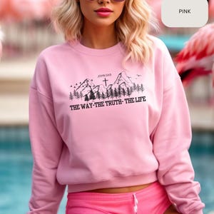 May include: Pink sweatshirt with a mountain scene and the text "JOHN 14:6 THE WAY-THE TRUTH-THE LIFE" printed on the front.