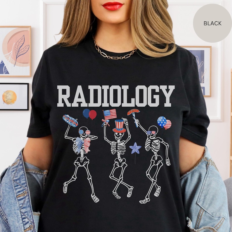Może przedstawiać: Czarny T-shirt z napisem "RADIOLOGY" w białych literach. Koszulka przedstawia grafikę trzech szkielet&oacute;w ubranych w czerwono-biało-niebieskie patriotyczne stroje, trzymających amerykańskie flagi, hot dogi i balony.