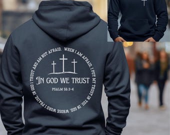 May include: Navy blue hoodie with a white circle graphic on the back. The graphic features three crosses and the text "In God We Trust" with the scripture reference "Psalm 56:3-4".