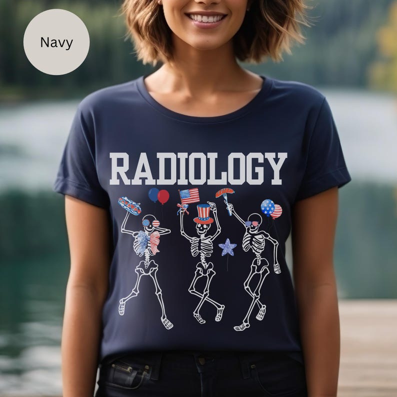 Może przedstawiać: Koszulka w kolorze granatowym z napisem "RADIOLOGY" w białych literach. Koszulka przedstawia grafikę trzech szkielet&oacute;w ubranych w czerwono-biało-niebieskie stroje patriotyczne, świętujących z balonami, hot dogiem i parasolką.