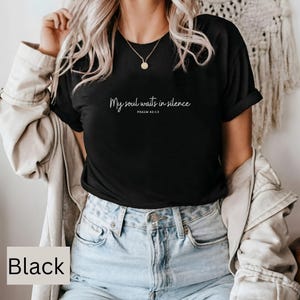 Op de afbeelding: Een zwart T-shirt met de tekst "My soul waits in silence Psalm 62:1:5" in witte letters.