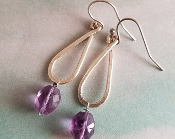 Faceted oval violet amethyst beads are hung from hand forged hammered silver tear drops with silver ear wires.
