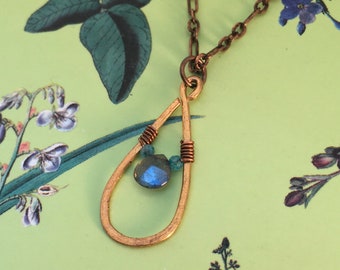 A tiny faceted labradorite is wire wrapped within A hand formed brass tear drop and hung on copper chain.