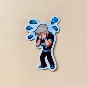 May include: A sticker of a cartoon character with blonde hair, wearing a black shirt and pants, with blue tears coming from their eyes. The character is covering their face with their hands.