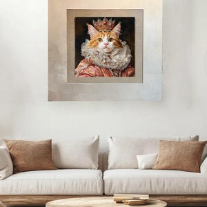 Pu&ograve; includere: Un ritratto incorniciato di un gatto che indossa una corona e un colletto a volant rosa e bianco. Il gatto ha il pelo arancione e gli occhi verdi. La cornice &egrave; argentata con un bordo interno dorato.