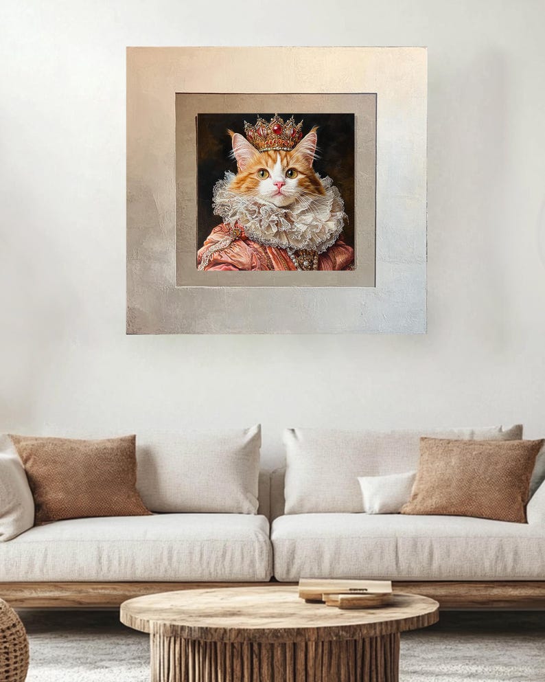 Pu&ograve; includere: Un ritratto incorniciato di un gatto che indossa una corona e un colletto a volant rosa e bianco. Il gatto ha il pelo arancione e gli occhi verdi. La cornice &egrave; argentata con un bordo interno dorato.
