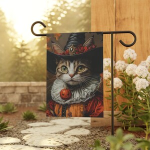 May include: A Halloween-themed garden flag featuring a cat dressed as a witch. The cat is wearing a black witch hat with a red rose and a pumpkin charm. The cat has green eyes and white fur on its chest. The flag is a dark brown color with a vintage style.