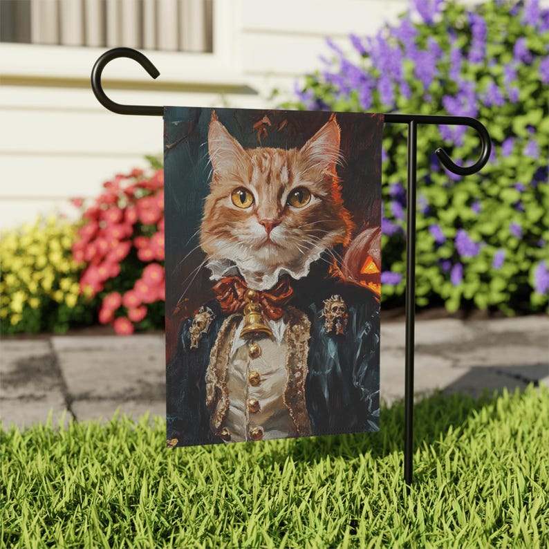 May include: A garden flag featuring a portrait of a ginger cat dressed in a blue and gold costume with a bell around its neck. The cat has a serious expression and is looking directly at the viewer. The background is a dark, blurry forest scene.