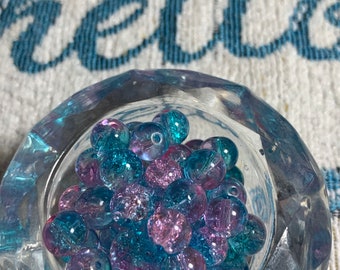 May include: A clear glass bowl filled with blue and pink iridescent glass beads.