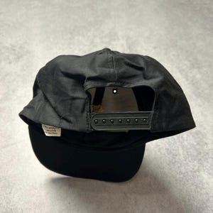 Pu&ograve; includere: Cappellino da baseball nero con visiera curva. Il cappellino ha una chiusura a scatto e una piccola etichetta con testo. Realizzato in un tessuto resistente, &egrave; progettato per adattarsi alla maggior parte delle dimensioni della testa.