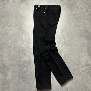 May include: A pair of black denim jeans, featuring a standard five-pocket design. The jeans are displayed flat on a grey surface, highlighting the stitching and back pockets. The dark wash provides a versatile appearance.