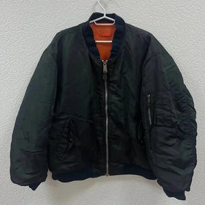May include: A black bomber jacket with a zip fastening and a contrasting orange lining. The jacket has a ribbed collar and cuffs.