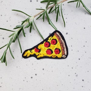 May include: A yellow and red embroidered iron-on patch of a pizza slice with pepperoni.