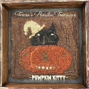 May include: A framed, textured artwork featuring a black cat atop an orange pumpkin, with a full moon in the background. The artwork is labeled "Pumpkin Kitty" and "Teresa's Primitive Treasures". The piece is set in a rustic wooden frame.