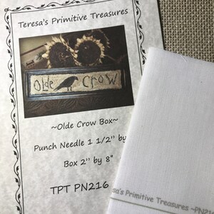 May include: A printed paper from "Teresa's Primitive Treasures" with the text "Olde Crow Box" and a crow illustration. The paper includes the text "Punch Needle 3.8 cm by Box 5 cm by 20 cm" and "TPT PN216". A white fabric is next to the paper.