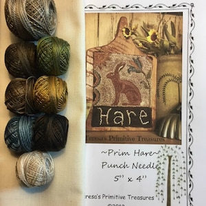 May include: A punch needle kit with a brown wooden cutting board featuring a brown hare with the word "Hare" stitched in brown yarn. The kit includes 8 balls of yarn in various shades of brown, green, and beige. The kit is 5 inches by 4 inches.