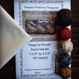 May include: A craft kit with the title "Peeps on Parade" featuring a punch needle design. The kit includes a piece of fabric, skeins of yarn in various colours, and instructions. The design measures 19 cm by 9 cm.